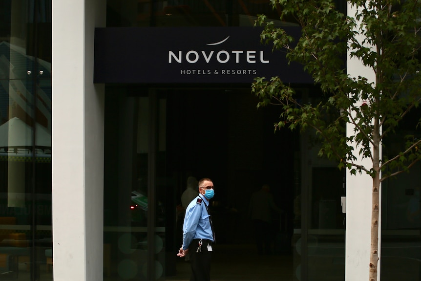 A masked security guard stands outside the entrance of the Novotel hotel, on Murray Street in Perth.
