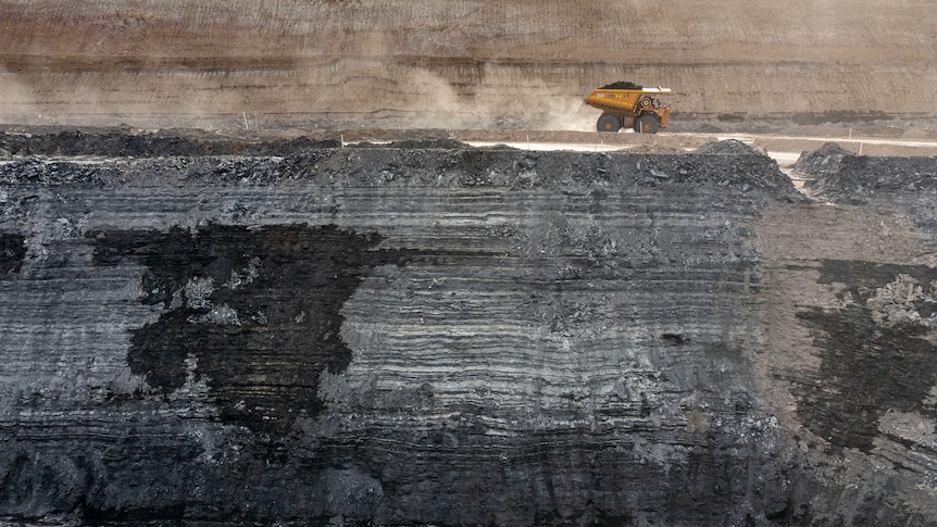 Photo of a truck driving along a mining shelf in a coal pit