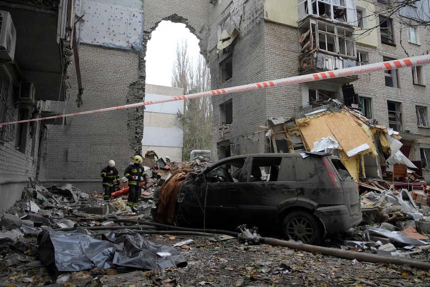 Emergency workers at the site of a shelled building.