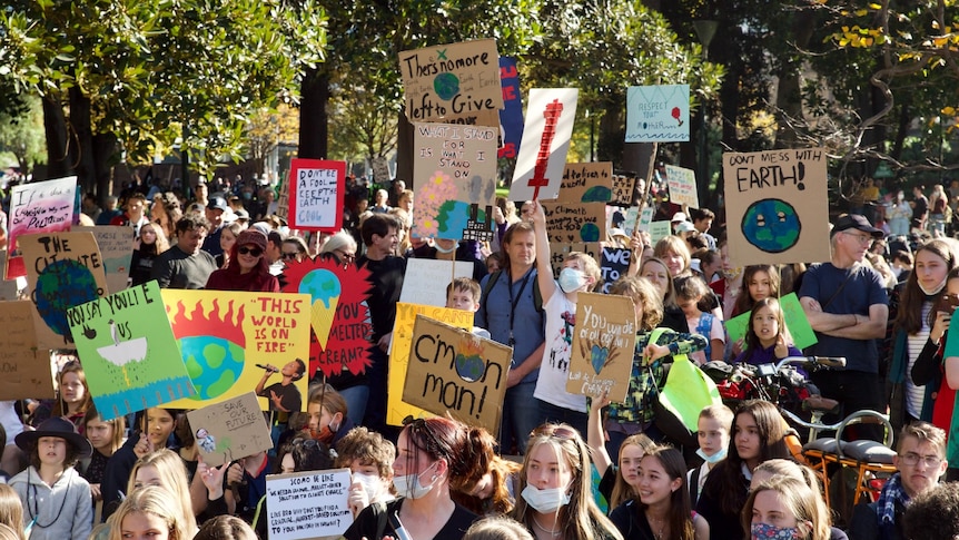 A large crowd of climate change protesters gathered in Melbourne, many holding signs.