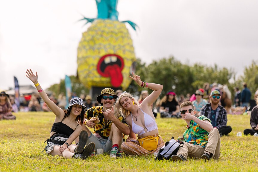 People enjoying festival, large pineapple behind