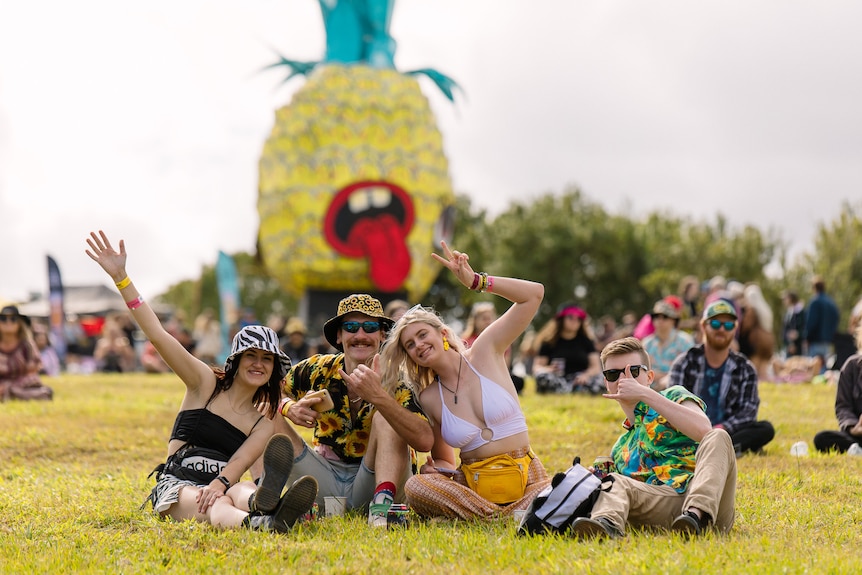 Люди наслаждаются фестивалем, позади большой ананас