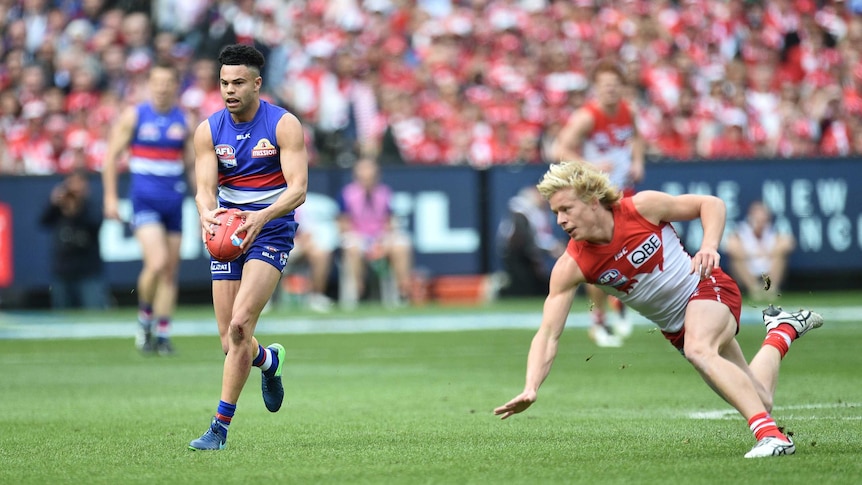 Jason Johannisen of the Bulldogs (L) is chased by Sydney's Isaac Heeney in the 2016 AFL grand final.