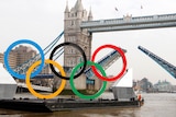 A barge with the Olympic rings mounted on it approaches Tower Bridge in London.