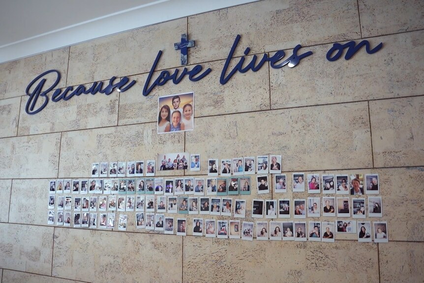 A wall with photos stuck underneath the words 'Because love lives on'