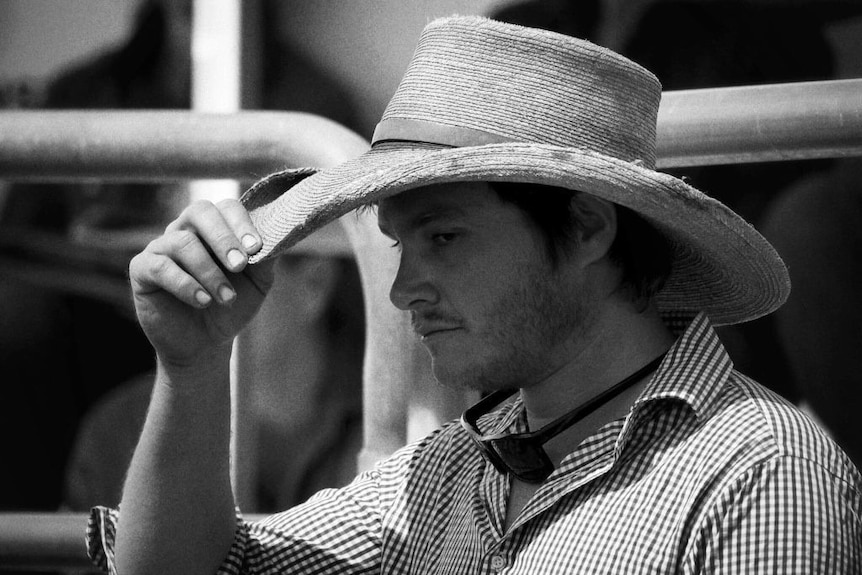 A close up of a grazier holding his hat