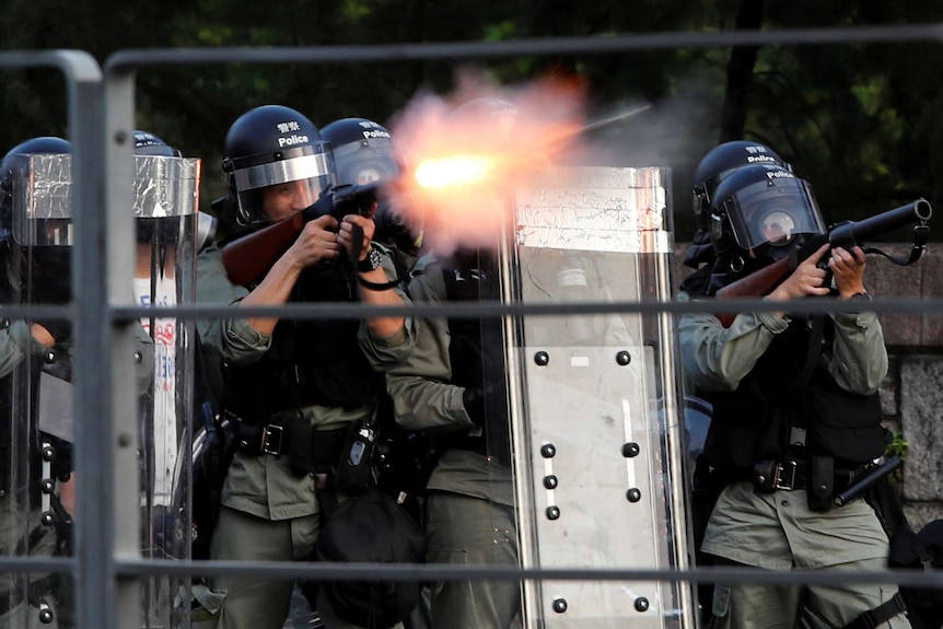 Hong Kong riot police shoot tear gas from behind shields