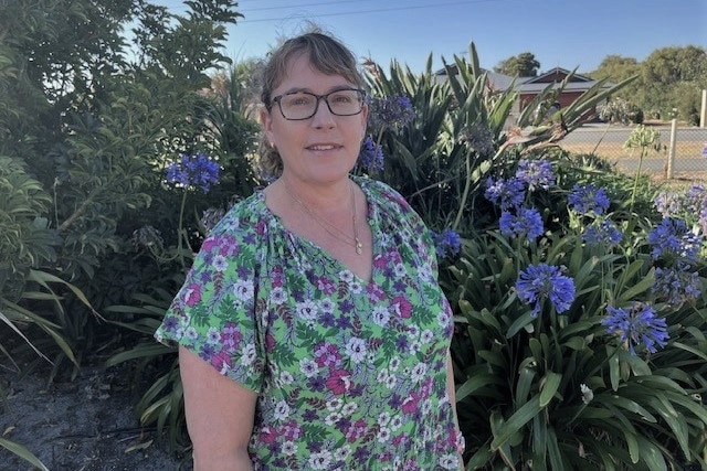 Danae standing in a garden with purple flowers.