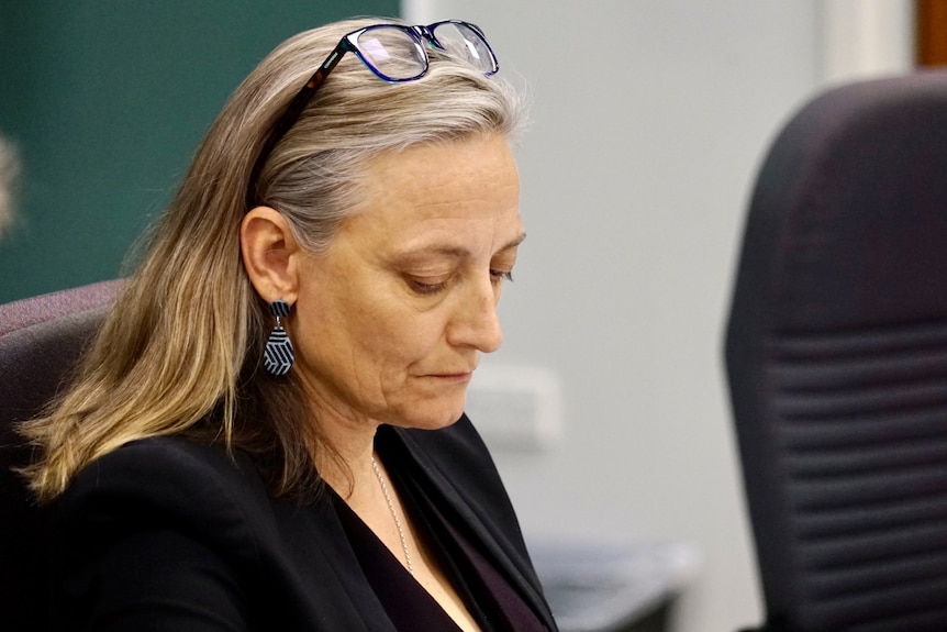 NT politician Kate Worden sits in NT Parliament looking down at some paperwork.