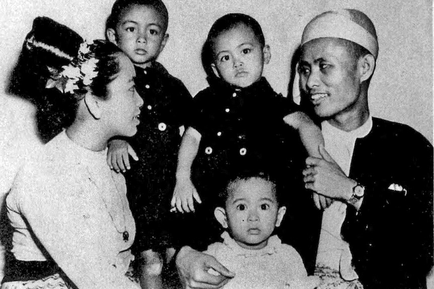 A black and white photo of Aung San Suu Kyi as a toddler sitting with her family