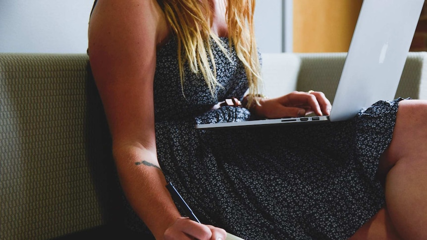 A young woman with a laptop computer takes notes.