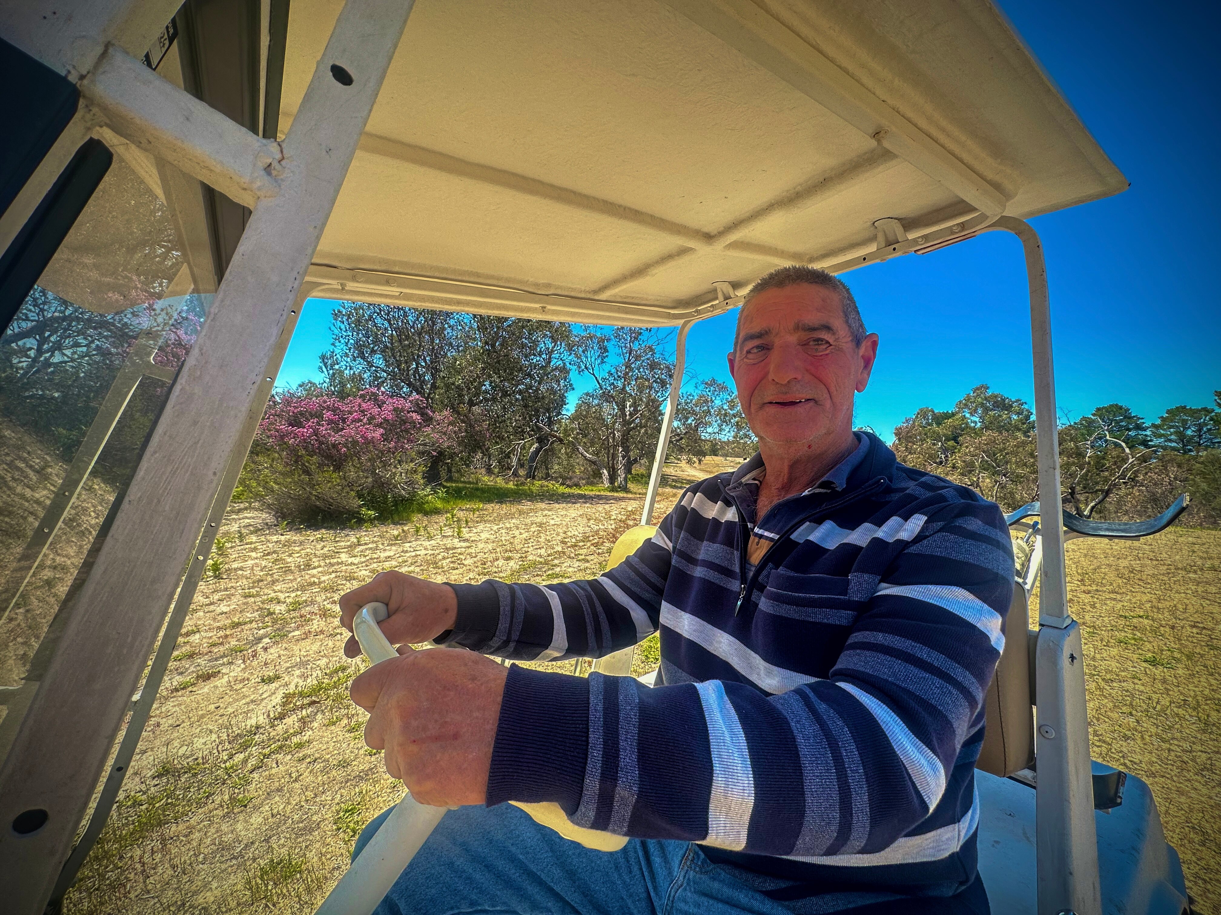 Man in blue and white striped polo sitting in golf caddy.