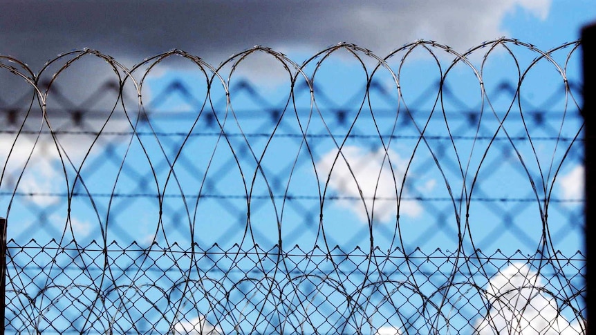 Razor wire is seen against a blue sky