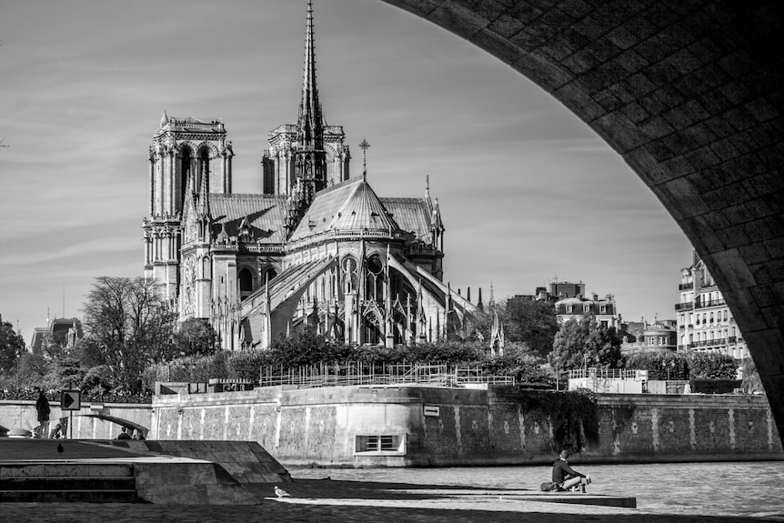 A black and white image of the Notre Dame cathedral before the fire as seen from the Seine.