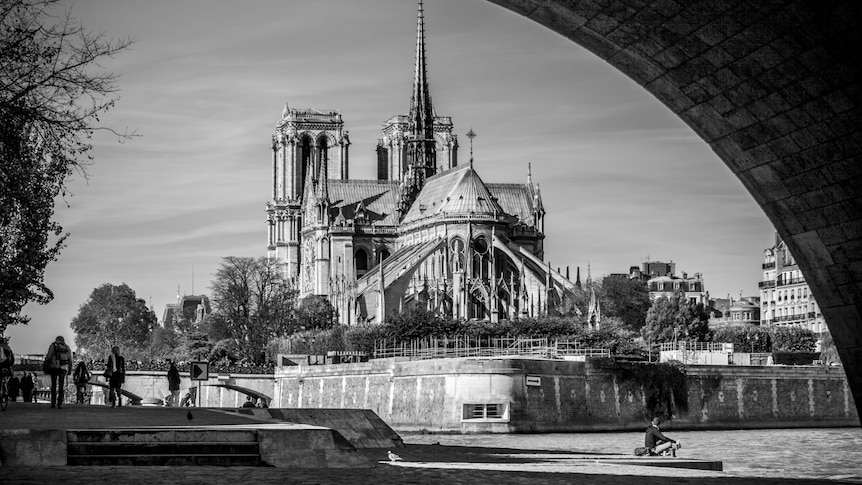 A black and white image of the Notre Dame cathedral before the fire as seen from the Seine.