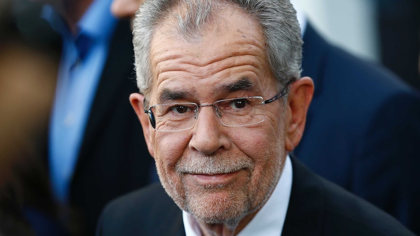 Alexander Van der Bellen, wearing glasses and a suit, smiles.