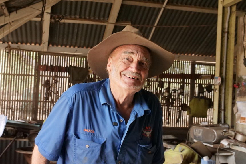 A smiling man in a hat, wearing a blue shirt with the name "BAZZA" embroidered on the chest. 