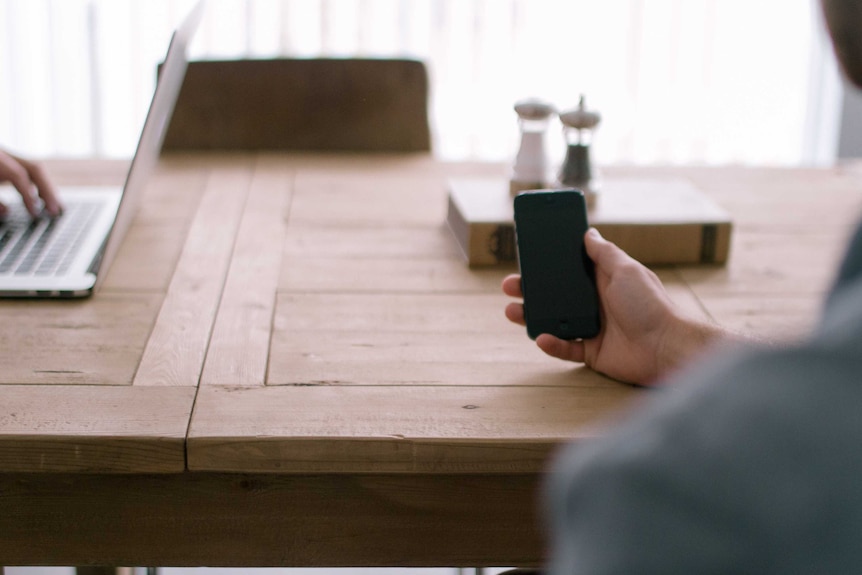 Person a phone, computer in the background