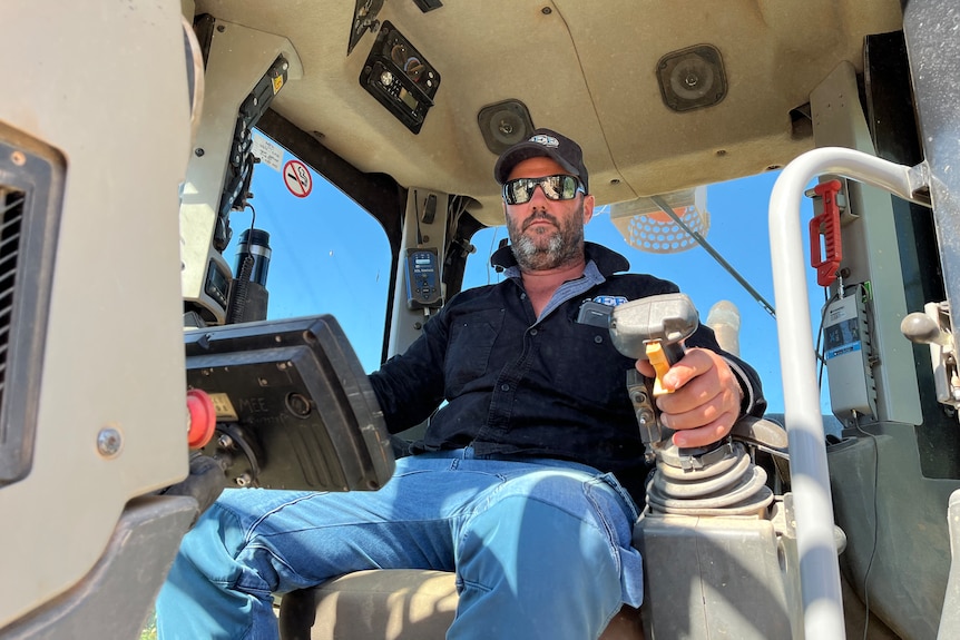 Steven Gallace sits inside the cabin of earth moving equipment