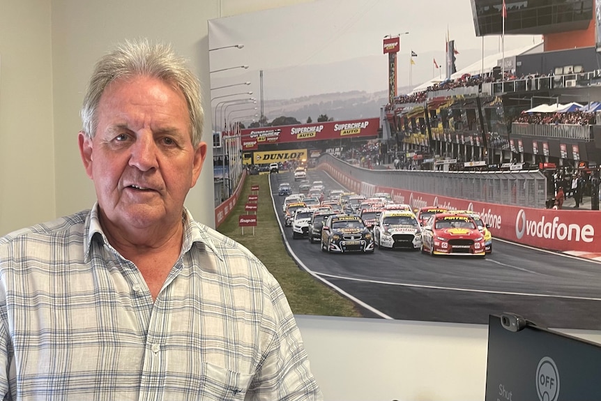 A man stands in front of a photo of the Bathurst 1000. 