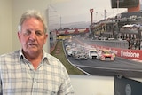 A man stands in front of a photo of the Bathurst 1000.