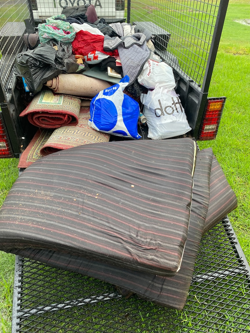 Old carpets and a sopping wet mattress in the back of a trailer.