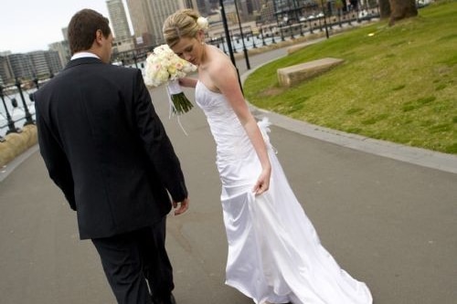 Ingrid Szajer looks down at her wedding dress while standing next to her husband Bruno.