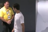 A freeze frame of security guard questioning Roger Federer.