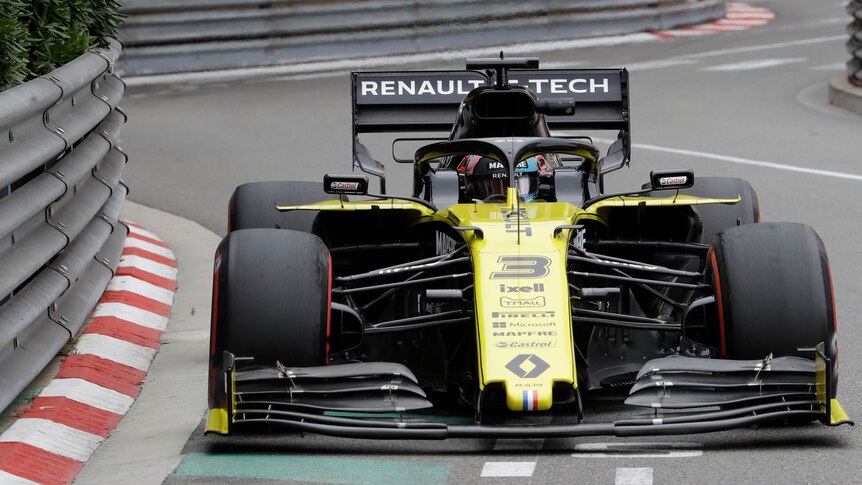 Daniel Ricciardo's yellow F1 car drives close to metal, armco barriers