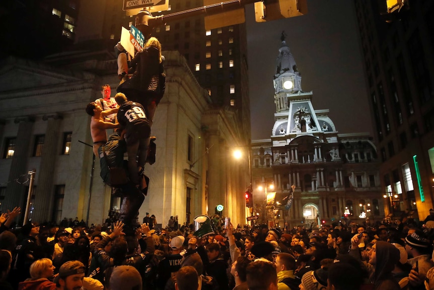 Several people climb poles on the street in downtown Philadelphia.