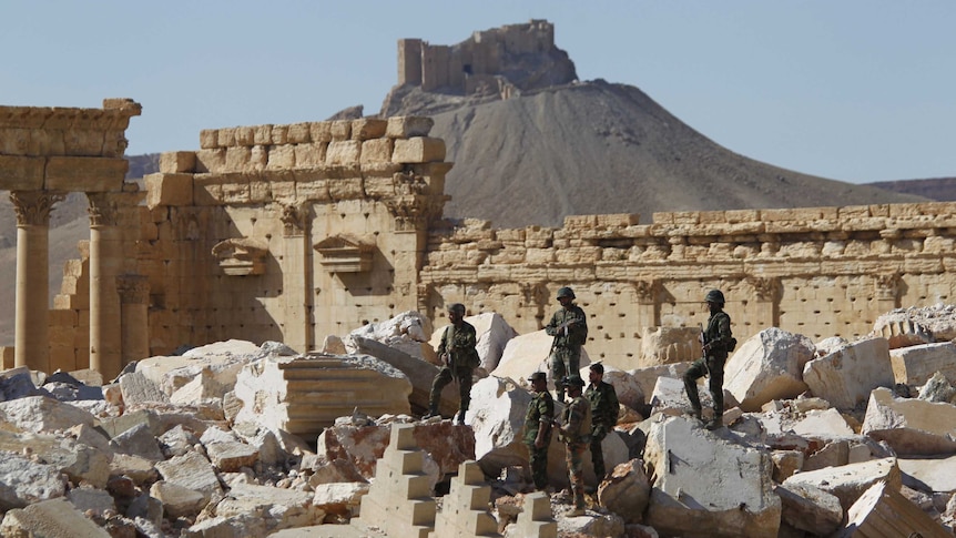 Syrian army soldiers stand on ruins in the historic city of Palmyra.