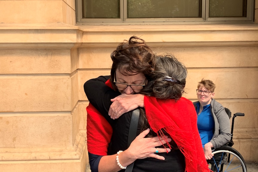 Two women hugging outside a courthouse