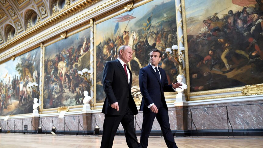Emmanuel Macron walks with Vladimir Putin through the Chateau de Versailles.