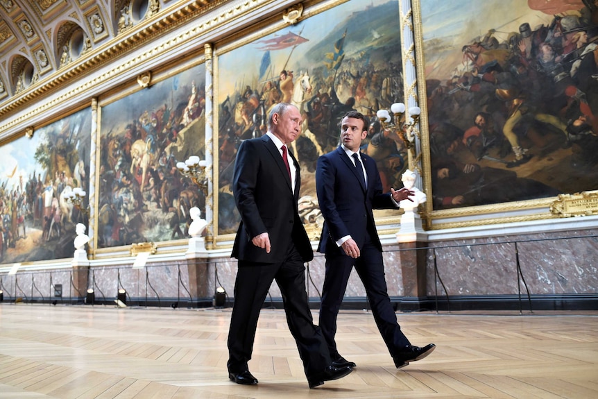 Emmanuel Macron walks with Vladimir Putin through the Chateau de Versailles.