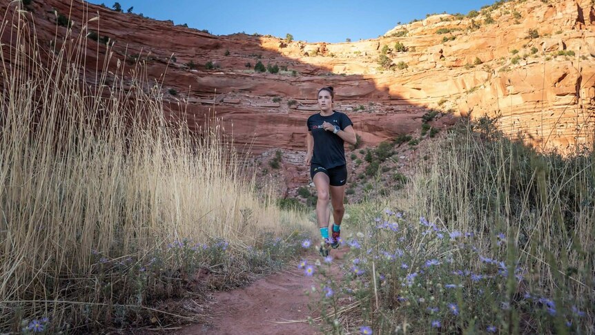 An athlete runs through rugged terrain in the Grand Canyon region of the USA.