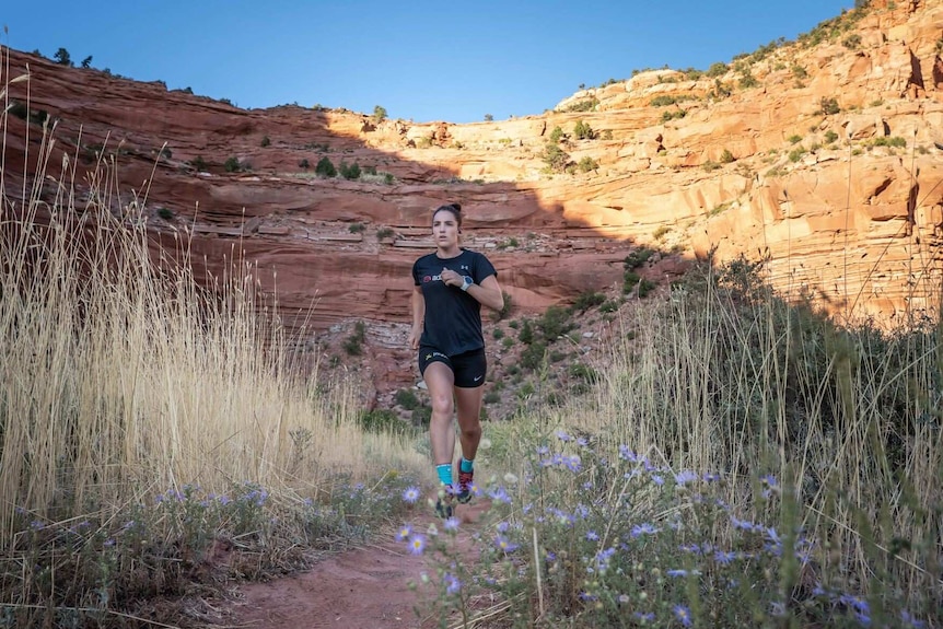 An athlete runs through rugged terrain in the Grand Canyon region of the USA.