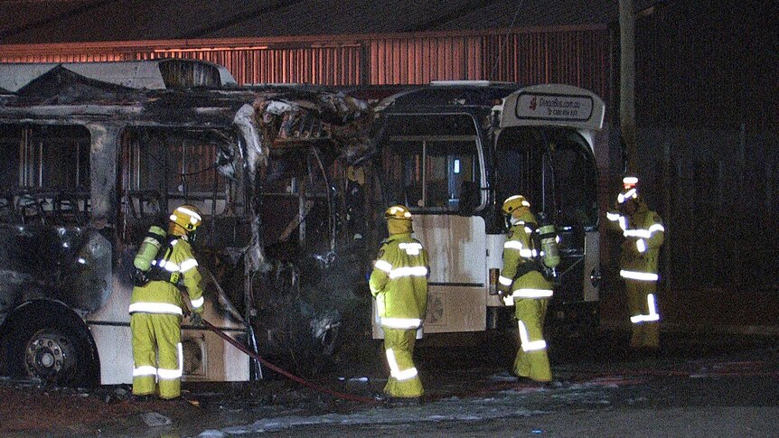 Firefighters spray foam at blackened buses