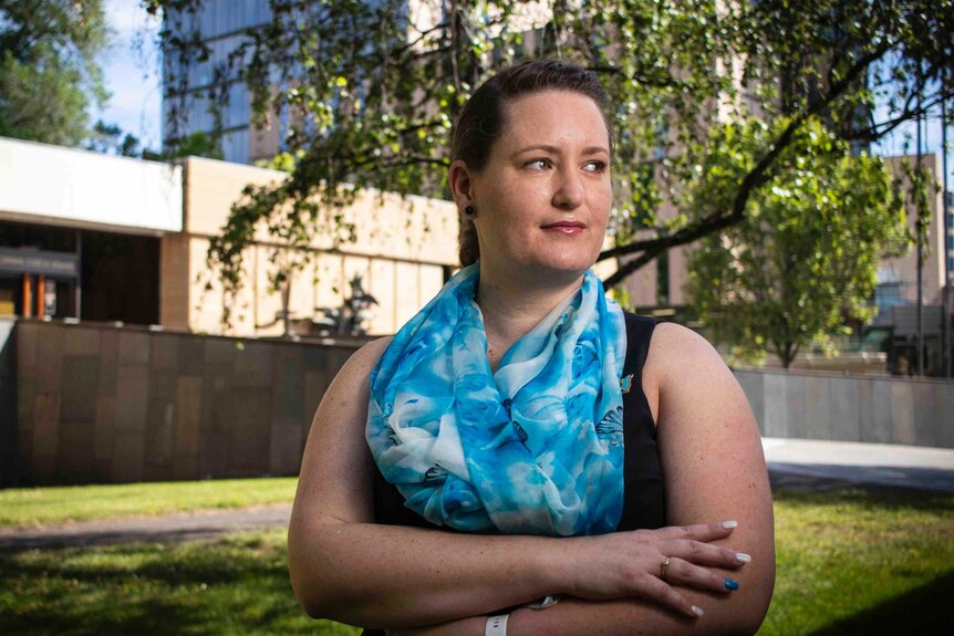 Sexual abuse survivor Katrina Munting folds her arms and looks off camera as she poses outside of Hobart's court