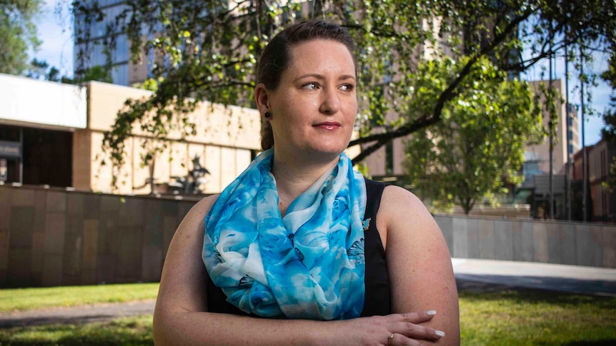 Sexual abuse survivor Katrina Munting folds her arms and looks off camera as she poses outside of Hobart's court