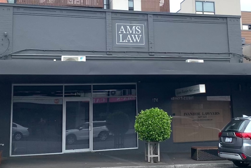 A single-storey office building in a suburban shopping strip with the words "AMS LAW".