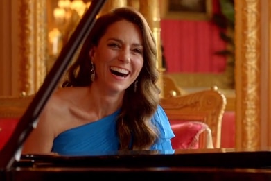 Kate Middleton sits in a blue dress whilst playing piano.