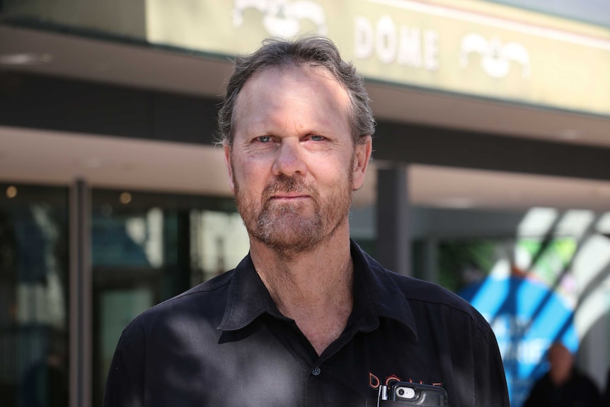 A man with a polo shirt on stands in front of a Dome Cafe sign