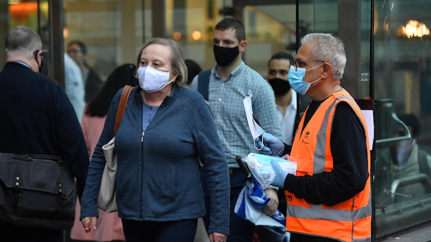 A group of commuters wear masks while walking outside.