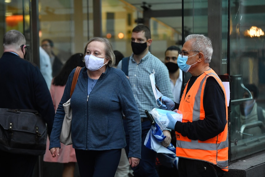 A group of commuters wear masks while walking outside.