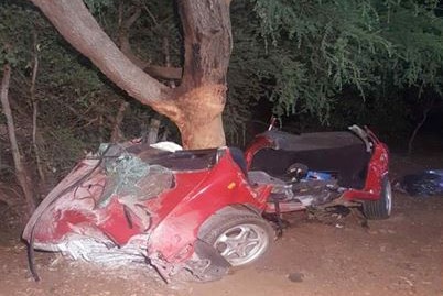 A wrecked red car wrapped around a tree.
