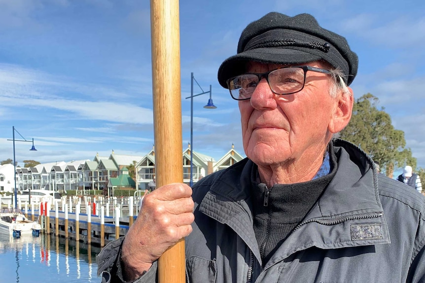 An elderly man standing on a boat jetty.