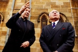 George Pell and John Howard pictured in front of a building, speaking to one another.