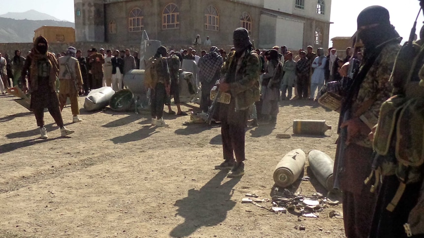 Afghan Taliban militants gather around parts of a US F-16 aircraft