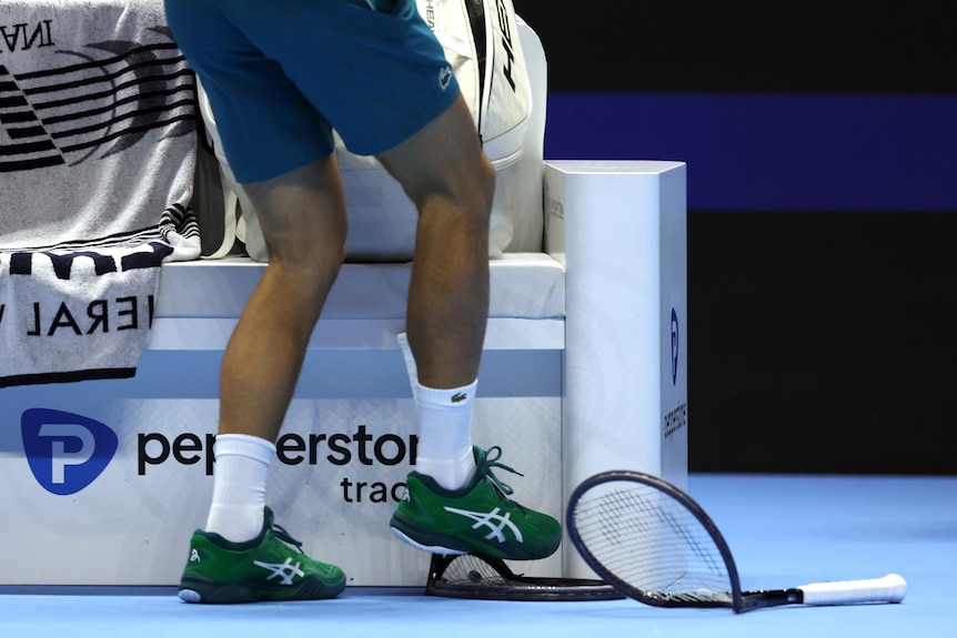 A racket is smashed with a foot.
