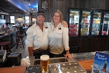 A man and a woman standing behind a bar